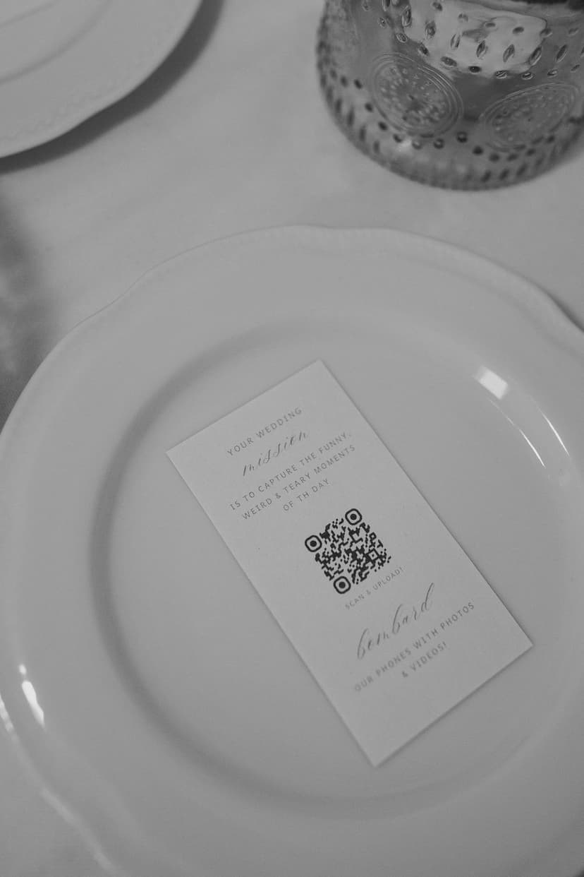 QR code card on a wedding plate setting with instructions for guests to scan and upload photos